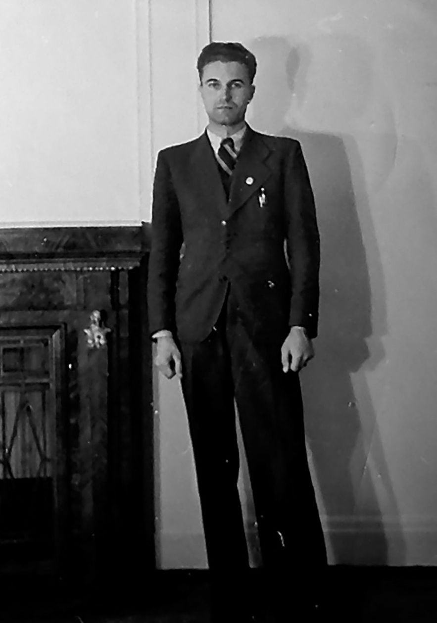 Totale eines Mannes in Anzug, wei&szlig;em Hemd, breitgestreifer Krawatte, Blick zur Kamera, Anstecker (vermutlich Hakenkreuz, aber das ist nicht genau zu erkennen) am Revers. &copy; Deutsches Bundesarchiv