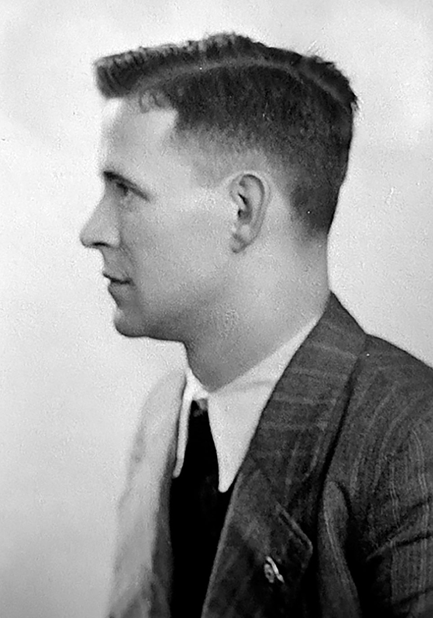 Profil von Mann mit Nadelstreifenanzug, wei&szlig;em Hemd, dunkler Krawatte und Hakenkreuz Pinnadel am Revers. Blickt in die Kamera &copy; Deutsches Bundesarchiv