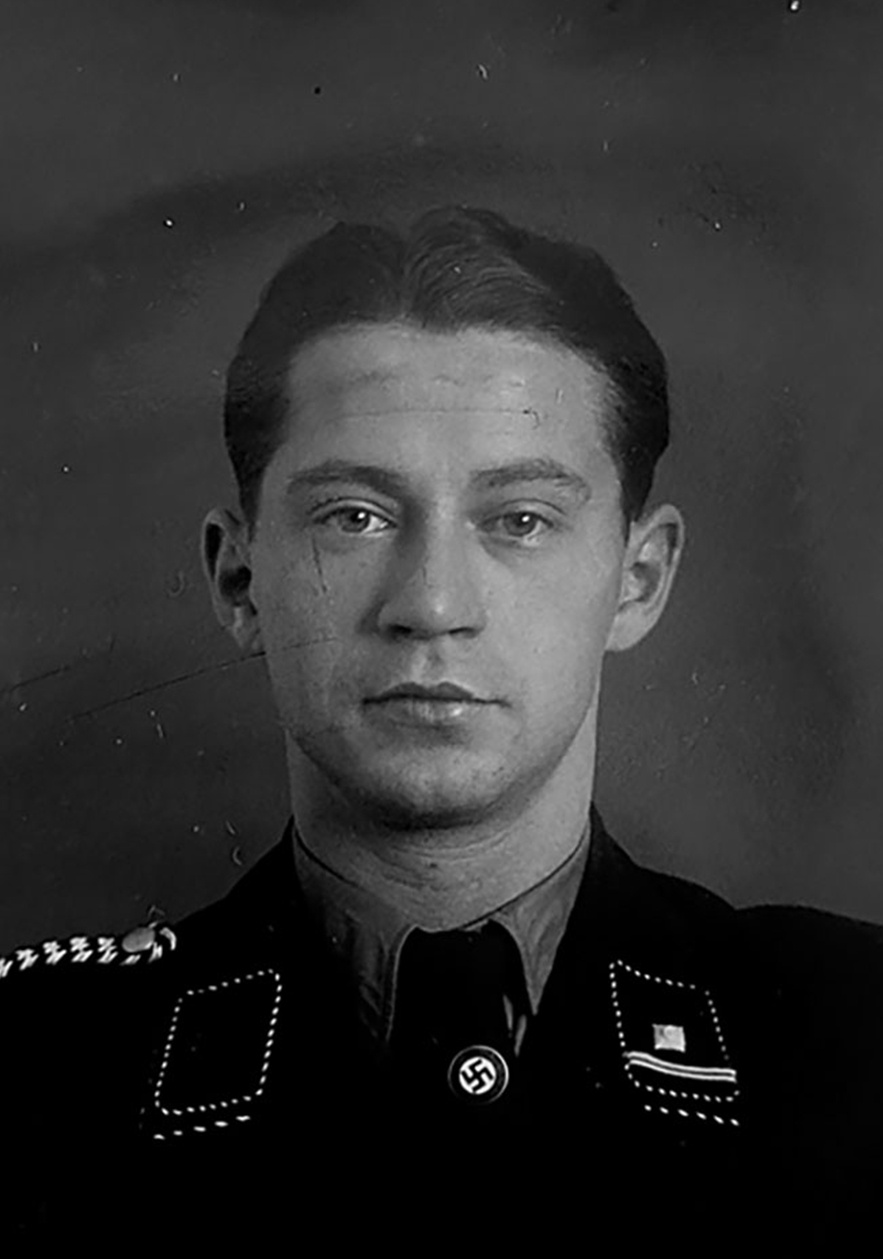 Frontalaufnahme von Mann mit Uniform, unter dem Krawattenknoten befindet sich eine Hakenkreuz-Pinnadel. Blick in die Kamera. &copy; Deutsches Bundesarchiv