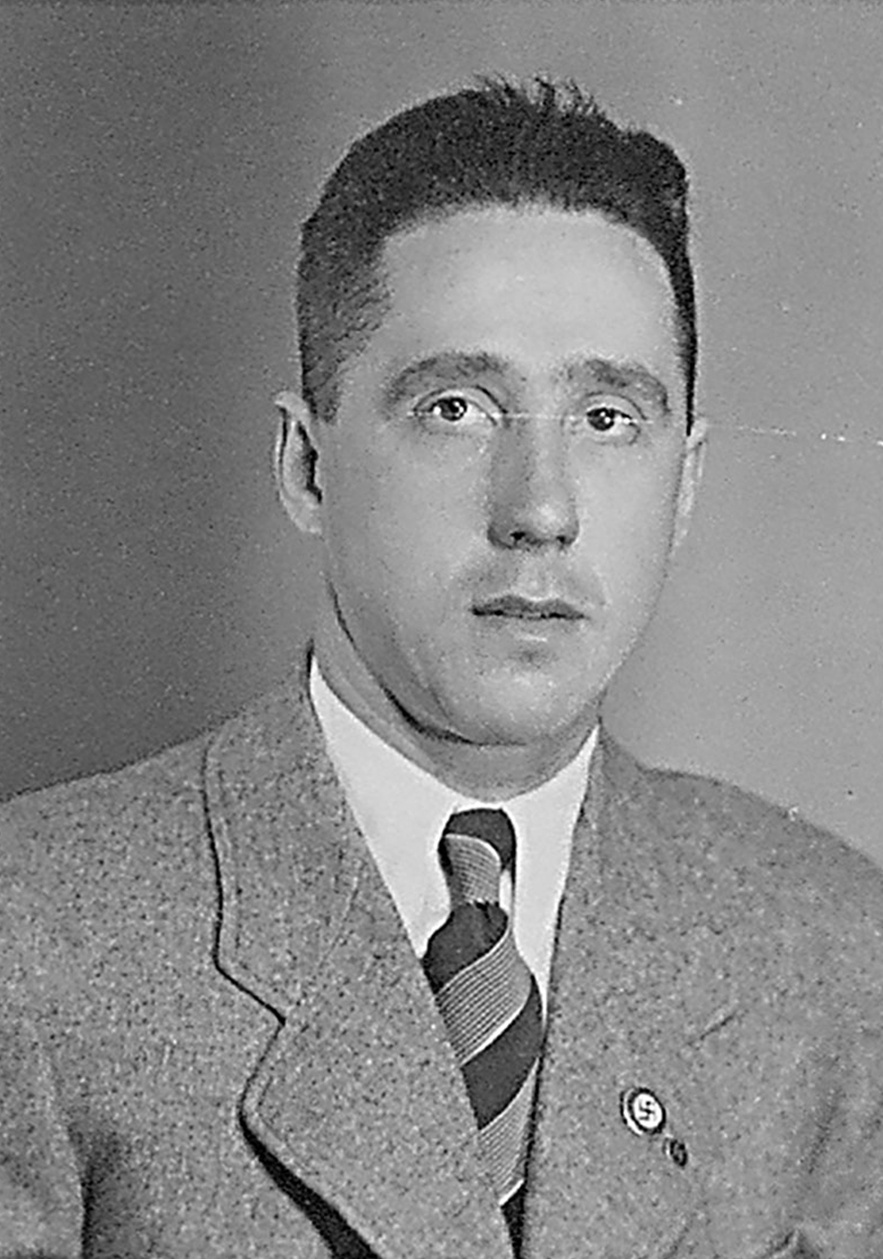 Frontalaufnahme von Mann in hellem Anzug, wei&szlig;em Hemd und breitgestreifter Krawatte, schaut zur Kamera. Hakenkreuz- und SS-Pinnadel am Revers. &copy; Deutsches Bundesarchiv