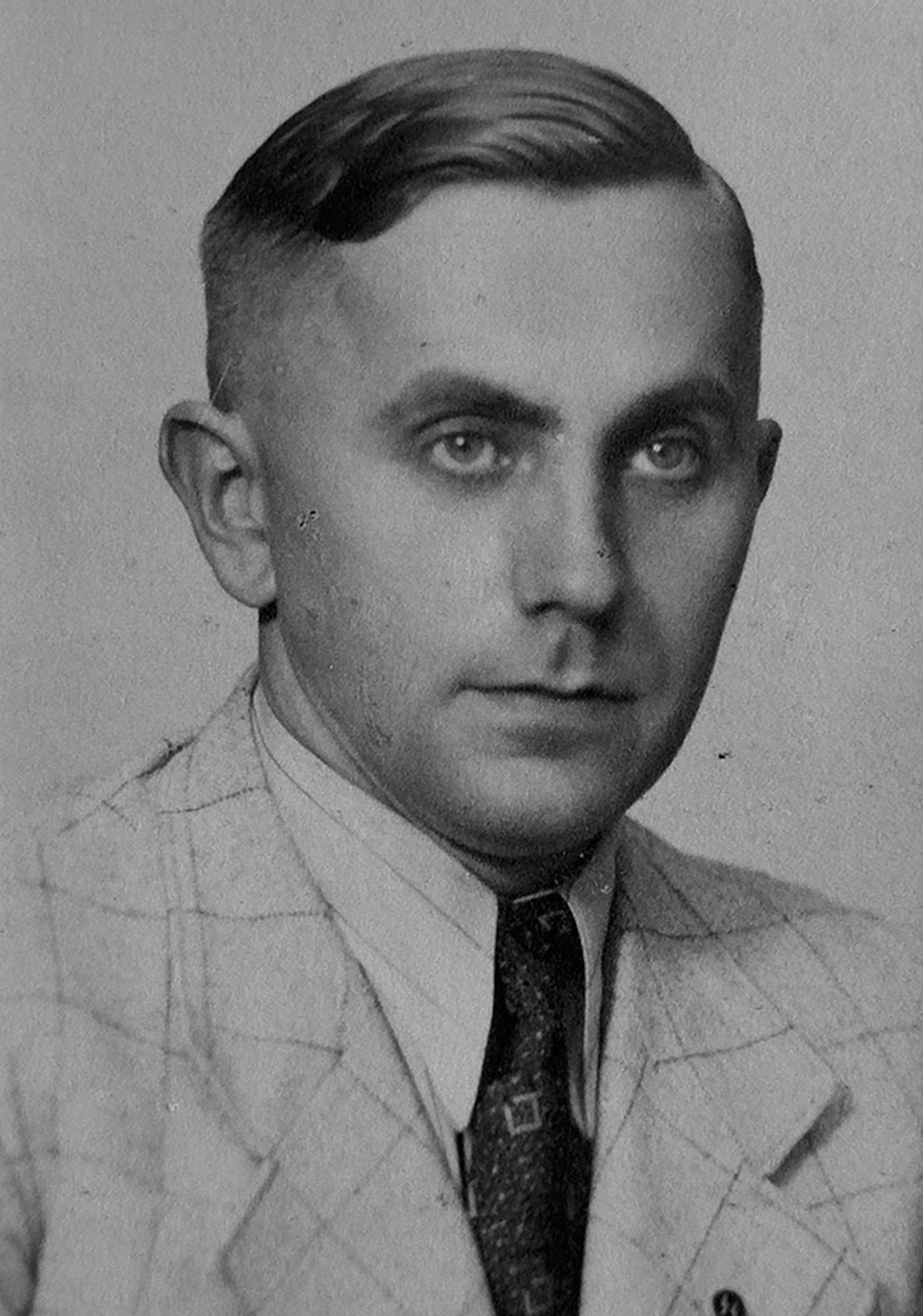 Halbprofil von Mann in hellem, kartierten Anzug, wei&szlig;em, leicht gestreiftem Hemd, gemusterter Krawatte und SS-Pinnadel am Revers. Blick rechts an der Kamera vorbei. &copy; Deutsches Bundesarchiv