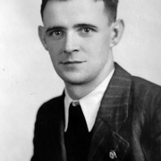 Halbprofil von Mann mit Nadelstreifenanzug, wei&szlig;em Hemd, dunkler Krawatte und Hakenkreuz Pinnadel am Revers. Blickt in die Kamera &copy; Deutsches Bundesarchiv