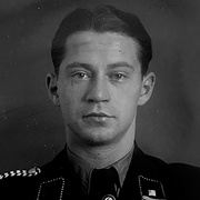 Frontalaufnahme von Mann mit Uniform, unter dem Krawattenknoten befindet sich eine Hakenkreuz-Pinnadel. Blick in die Kamera. &copy; Deutsches Bundesarchiv