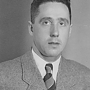 Frontalaufnahme von Mann in hellem Anzug, wei&szlig;em Hemd und breitgestreifter Krawatte, schaut zur Kamera. Hakenkreuz- und SS-Pinnadel am Revers. &copy; Deutsches Bundesarchiv