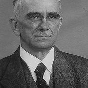 Frontal-Portrait von &auml;lterem Mann. Randlose Brille, eventuell ohne B&uuml;gel, Fischgr&auml;tenanzug und -Gilet, wei&szlig;es Hemd, gemusterte Krawatte, Hakenkreuz-Pinnadel am Revers. &copy; Wiener Stadt- und Landesarchiv